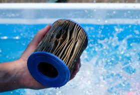 Dirty,Replacement,Pool,Filter,Cartridge,In,A,Hand,On,The Dirty,Replacement,Pool,Filter,Cartridge,In,A,Hand,On,The